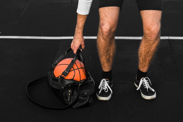 Kostenloses Foto nicht erkennbarer spieler hebt sporttasche an