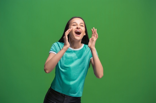 Nicht verpassen. Junge lässige Frau, die schreit. Schreien. Weinende emotionale Frau, die auf grünem Studiohintergrund schreit. Weibliches Porträt in halber Länge. Menschliche Emotionen, Gesichtsausdruckkonzept. Trendige Farben