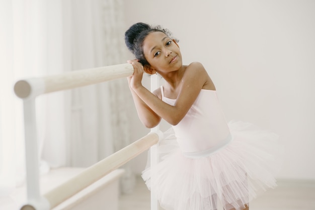 Niedliche kleine Ballerina im rosa Ballettkostüm. Kind in Spitzenschuhen tanzt im Raum. Kind im Tanzkurs.