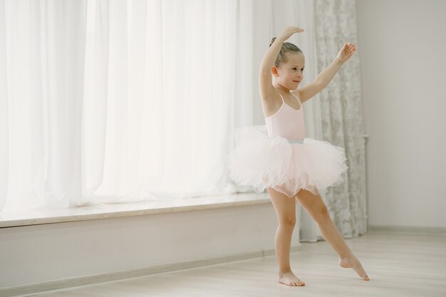 Niedliche kleine Ballerinas im rosa Ballettkostüm. Kind in Spitzenschuhen tanzt im Raum. Kind im Tanzkurs.