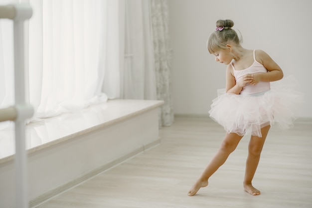 Niedliche kleine Ballerinas im rosa Ballettkostüm. Kind in Spitzenschuhen tanzt im Raum. Kind im Tanzkurs.