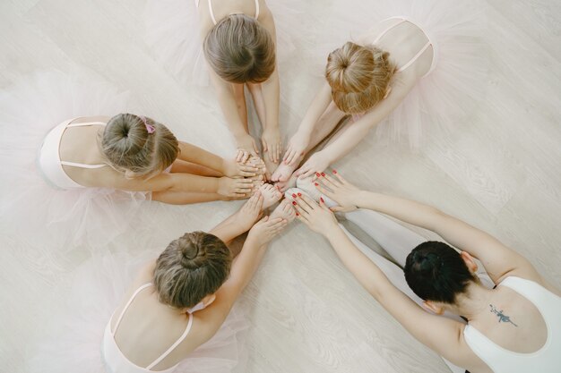 Niedliche kleine Ballerinas im rosa Ballettkostüm. Kinder in Spitzenschuhen tanzen im Raum. Kind im Tanzkurs mit Teatcher.