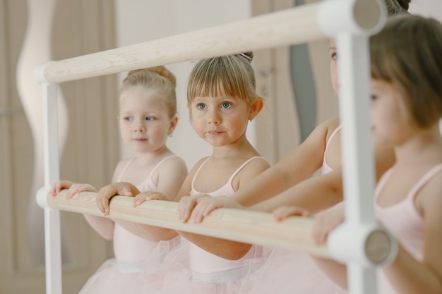 Kostenloses Foto niedliche kleine ballerinas im rosa ballettkostüm. kinder in spitzenschuhen tanzen im raum. kind im tanzkurs.