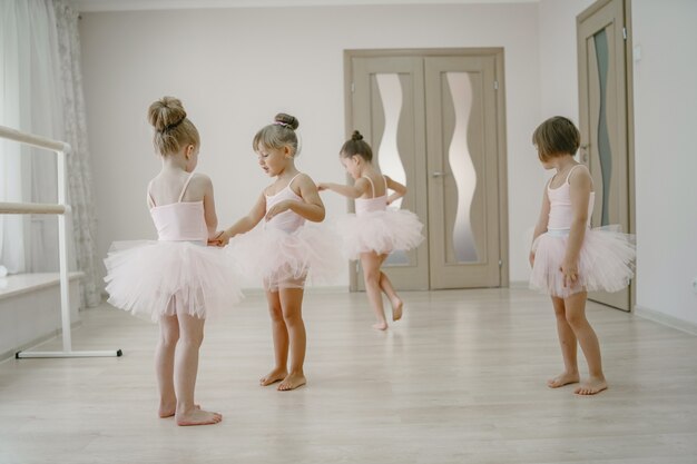 Niedliche kleine Ballerinas im rosa Ballettkostüm. Kinder in Spitzenschuhen tanzen im Raum