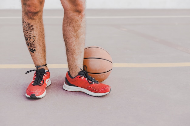 Niedrige Schnittansicht der Füße eines Mannes mit Basketball