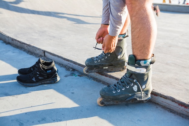 Niedrige Schnittansicht der Hand eines Mannes, die auf rollerskate sich setzt