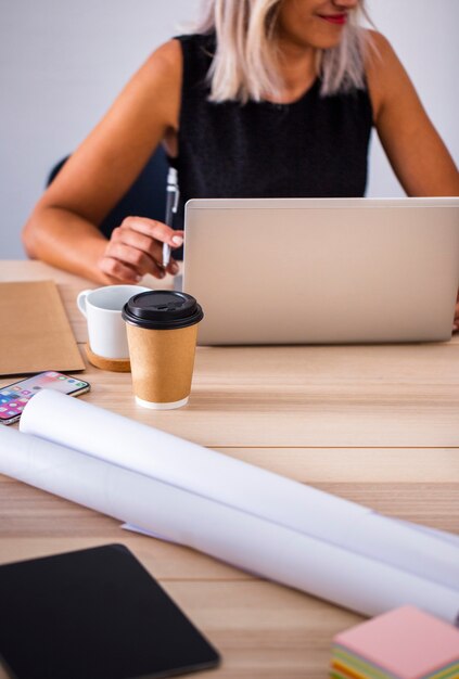 Niedrige Winkelfrau im Büro, das an Laptop arbeitet