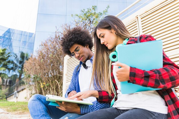 Niedrige Winkelsicht von den jungen verschiedenen Studenten, die zusammen vor Universitätsgebäude studieren