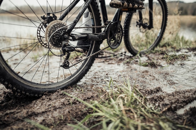 Niedriger Abschnitt der Füße des Radfahrers auf Fahrrad im Schlamm