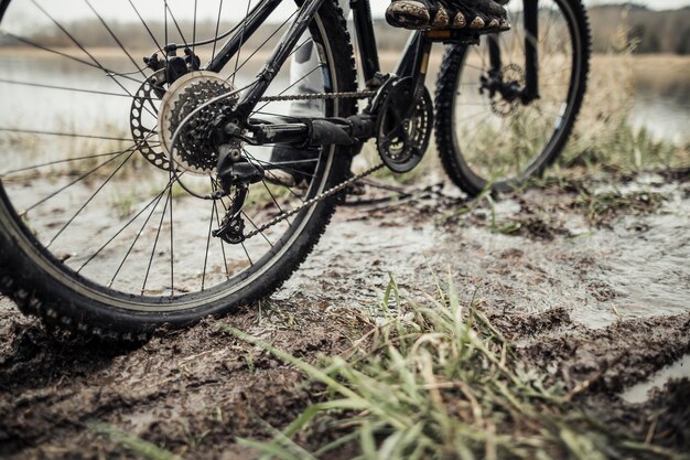 Niedriger Abschnitt der Füße des Radfahrers auf Fahrrad im Schlamm