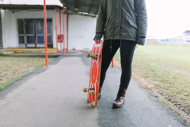 Niedriger Abschnitt einer Frau, die Skateboard auf Gehweg hält