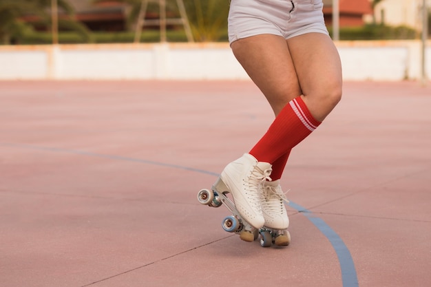 Niedriger Abschnitt eines weiblichen Schlittschuhläufers, der mit Rollschuh auf Gericht balanciert