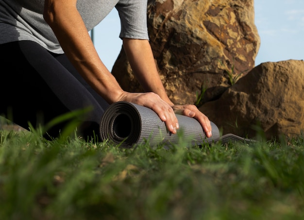 Kostenloses Foto niedriger winkel der frau, die yogamatte auf dem gras rollt