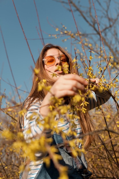 Niedriger Winkel der Frau mit Sonnenbrille, die mit Blumen aufwirft