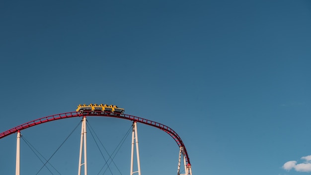 Niedriger Winkelschuss einer Achterbahn, die unter dem klaren blauen Himmel gefangen genommen wird