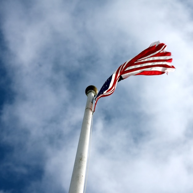 Niedriger Winkelschuss einer Flagge der Vereinigten Staaten mit einem bewölkten blauen Himmel