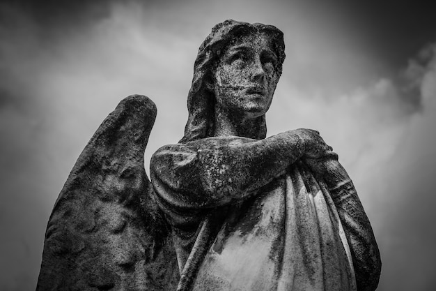 Niedriger Winkelschuss einer weiblichen Statue mit Flügeln in Schwarzweiss