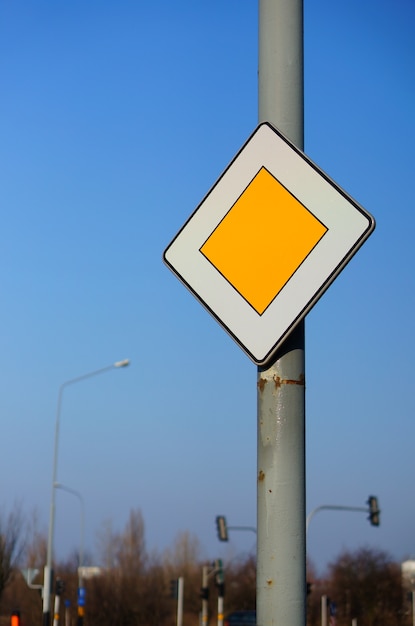 Niedriger Winkelschuss eines vorrangigen Verkehrszeichens unter einem klaren blauen Himmel