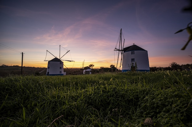 Niedriger Winkelschuss von Windmühlen mit einem Sonnenaufgang in einem klaren lila Himmel im Hintergrund