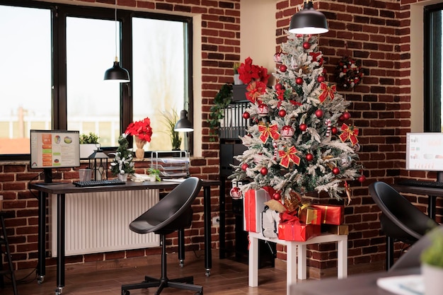 Niemand im Geschäftsbüro mit Christbaumschmuck, festlicher Weihnachtsdekoration und Lichtern, um die Wintersaison beim Startjob zu feiern. Keine Menschen am Arbeitsplatz des Unternehmens, die mit Weihnachtsschmuck gefüllt sind.