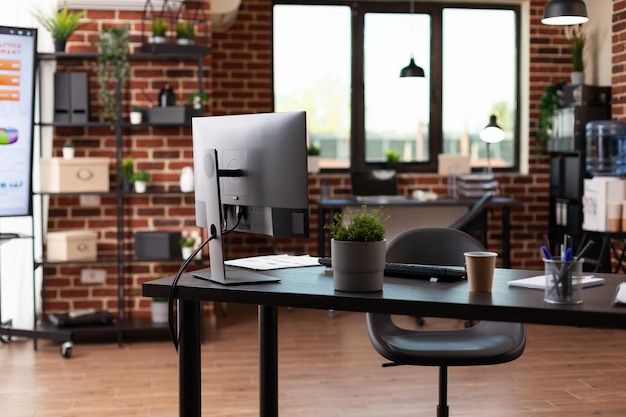 Niemand im Geschäftsbüro mit Computer und Instrumenten auf dem Schreibtisch. Leerer Startup-Raum, um mit Monitor und Ausrüstung am Unternehmenswachstum zu arbeiten. Keine Menschen am Arbeitsplatz mit Dekorationen.