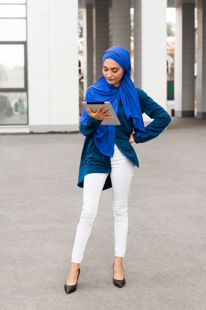 Nobler Teenager mit Hijab, der auf ihrem Tablett schaut