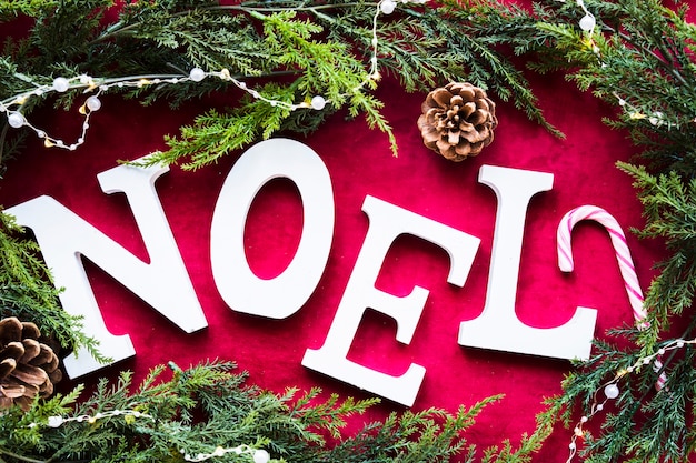 Noel-Titel zwischen Haken und grünen Nadelzweigen