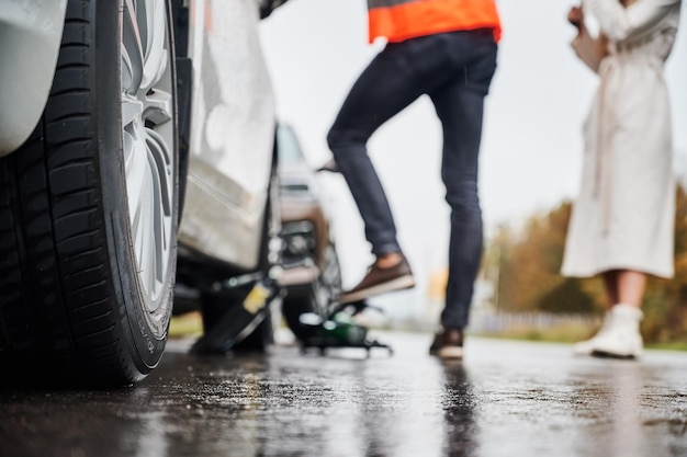 Notautomechaniker, der Frauenfahrzeug auf der Straße repariert