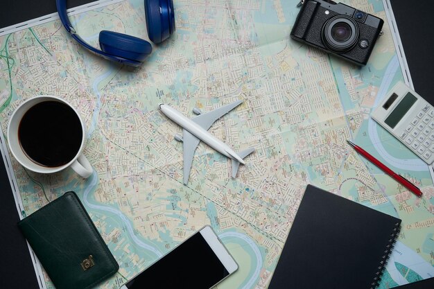 Notebook, kamera, flugzeug, stift, taschenrechner und karte des reisenden auf schwarzem hintergrund mit kopienraum. reisekonzept.