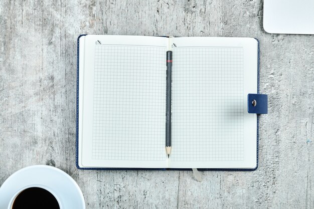 Notebook, Laptop und eine Tasse Tee auf dem Schreibtisch aus Holz.