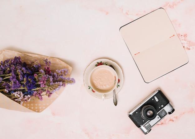 Kostenloses Foto notizbuch mit kaffeetasse, kamera und blumenblumenstrauß auf tabelle