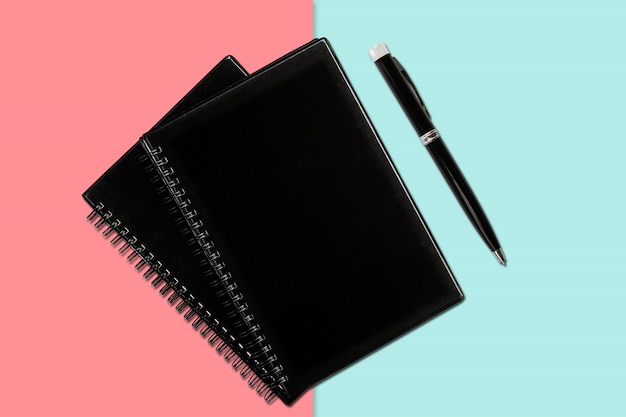 Notizbuch und Stift auf farbigem Hintergrund