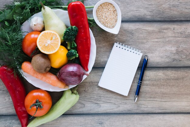 Notizbuch und Stift nahe Obst und Gemüse