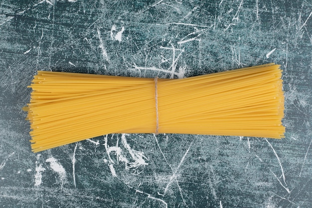 Nudelbündel von Vollkornspaghetti gebunden mit Seil auf Marmorhintergrund. Hochwertiges Foto