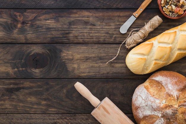 Kostenloses Foto nudelholz in der nähe von brotlaiben