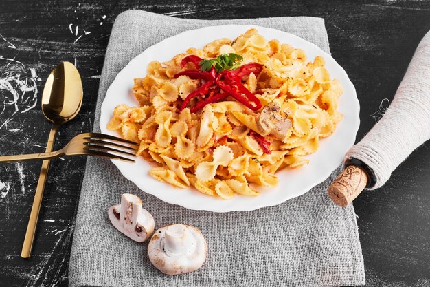 Nudeln in Tomatensauce in einem weißen Teller mit Besteck beiseite gestellt.