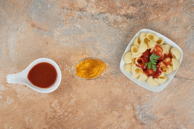 Nudeln mit Petersilie und Sauce auf orangefarbenem Hintergrund mit Öl