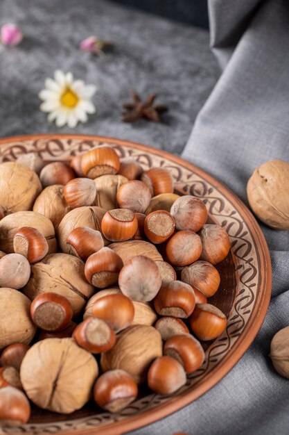 Nüsse und Walnüsse in einer Keramikschale und auf der Tischdecke mit Gänseblümchen herum