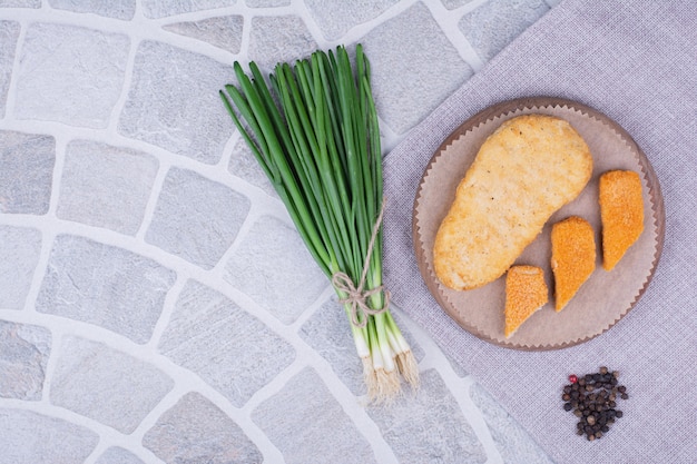 Nuggets auf einem Holzbrett mit einem Bund Frühlingszwiebeln