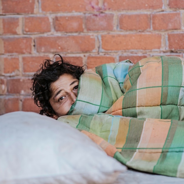 Obdachlose Frau mit Decke und Kissen im Freien