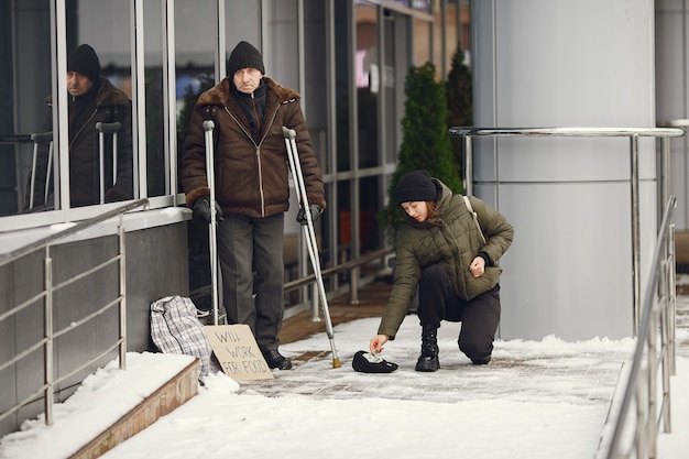 Obdachlose in einer Winterstadt. Mann, der um Essen bittet.