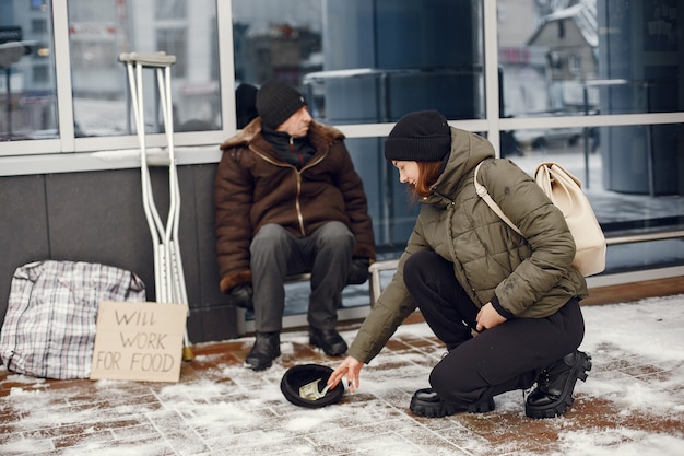 Obdachlose in einer Winterstadt. Mann, der um Essen bittet.