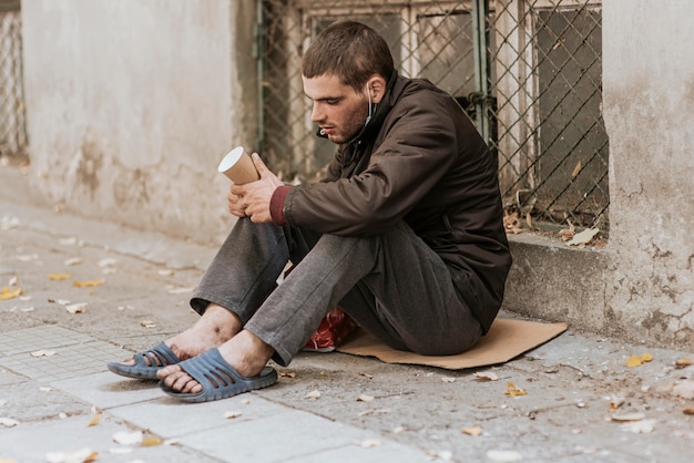 Obdachloser auf der Straße mit Tasse