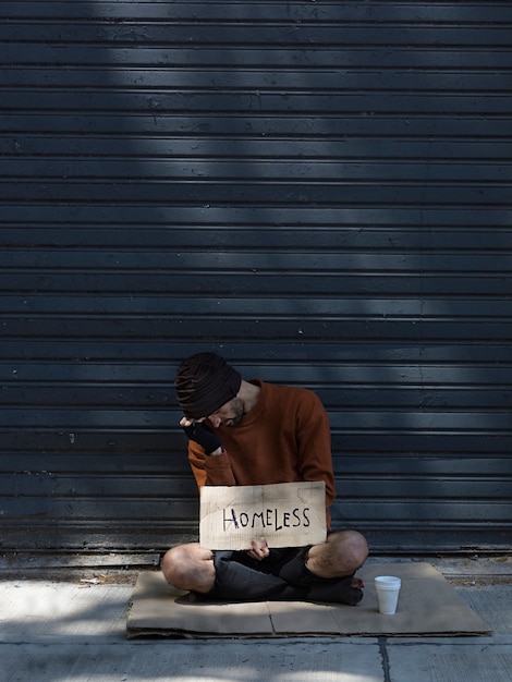 Kostenloses Foto obdachloser mann versteckt sein gesicht und bittet um geld lange sicht