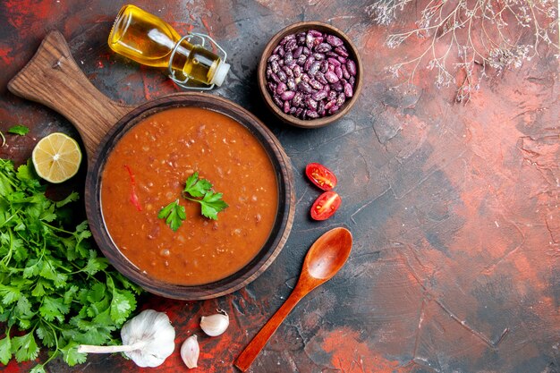 Oben Ansicht der Tomatensuppe auf einem braunen Schneidebrett auf einer gemischten Farbtabelle