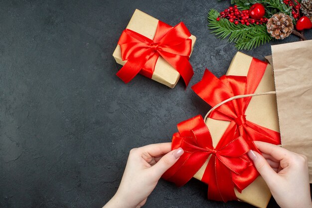 Oben Ansicht der Weihnachtsstimmung mit schönen Geschenken mit rotem Band auf der rechten Seite auf dunklem Hintergrund