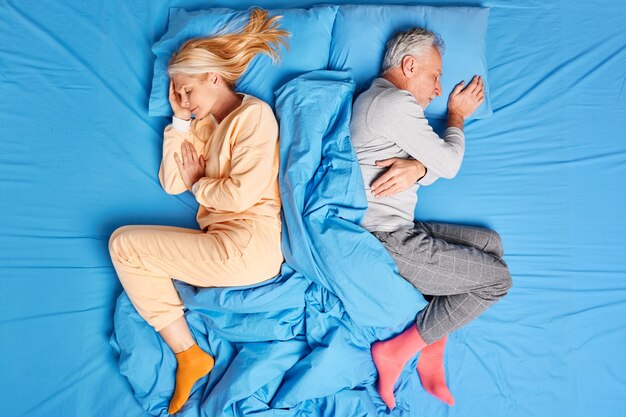 Oben Ansicht des verheirateten alten Ehepaares schlafen tief zurückliegend in bequemen Betten tragen weiche Pyjamas haben gute Ruhe nach einem harten Arbeitstag genießen gemütliche Atmosphäre. Menschen schlafen Konzept