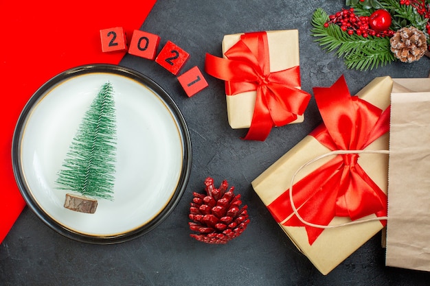 Oben Ansicht des Weihnachtsbaumes auf einem Teller Nadelbaumkegel Tannenzweige nummeriert schöne Geschenke auf einem dunklen Tisch