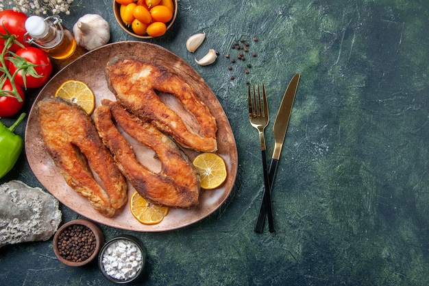 Oben Ansicht von gebratenen Fischen und Zitronenscheiben auf einer braunen Platte würzt Tomatenölflasche auf Mischfarbtabelle mit freiem Raum