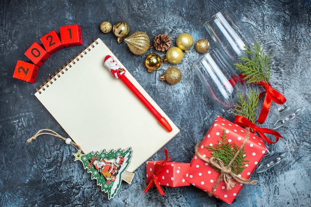 Oben Blick auf gefallene Glasbecher und Besteckset Dekorationszubehör Geschenkbox und Weihnachtssockennummern auf dunklem Tisch